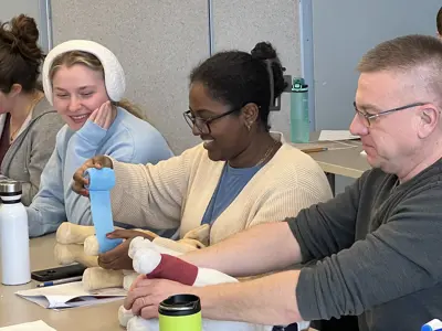 Participants bandaging a stuffed dog in a pet first aid class